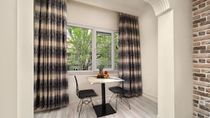A dining area with a table and chairs, a fruit bowl on the table, and a view of trees outside the window. - İSTANBUL HOTEL SUİTES (İstanbul)