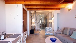 A modern living room with a wooden ceiling, a staircase, a sofa, and a dining area.