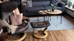 Ein modernes Wohnzimmer mit einem dunkelgrauen Sofa, einem Ledersessel und einem runden Couchtisch.