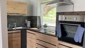 Eine moderne Küche mit Holzausstattung, einem Einbauofen und einem Fenster mit Jalousien.