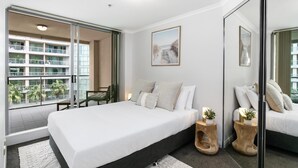 Un dormitorio moderno con una cama grande, vistas a un edificio y un balcón.