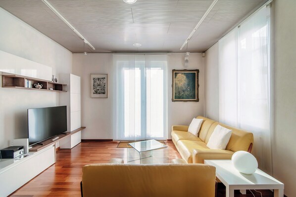 컴포트 아파트, 발코니, 정원 전망 | 거실 공간 | 디지털 채널 시청이 가능한 32인치 평면 TV