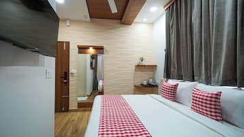 A hotel room with a bed, a wooden ceiling, a wall with a wavy pattern, a bedside table with a plant, and a window with curtains.