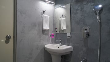 A bathroom with a white sink, a mirror, a handheld showerhead, and a towel rack.