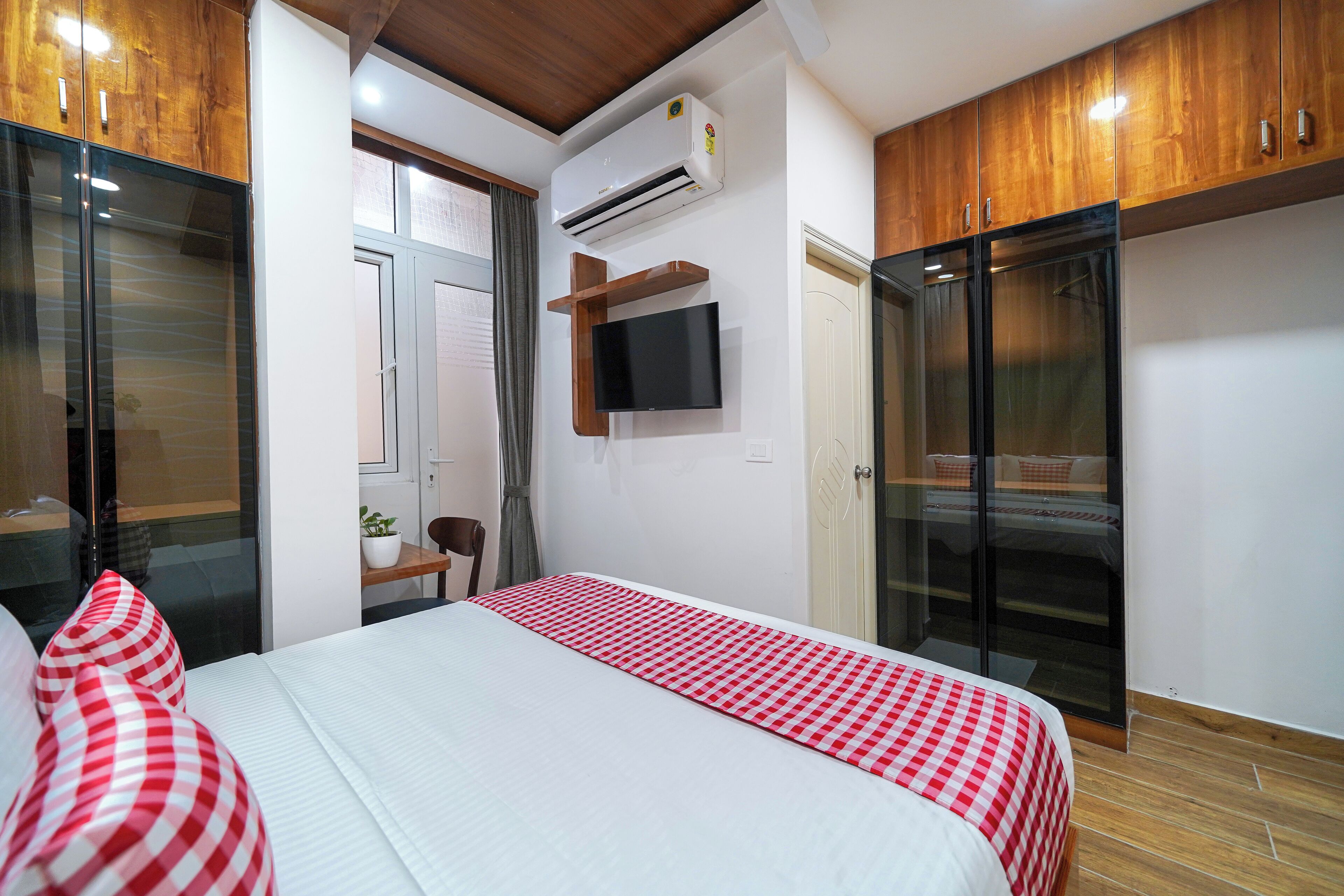 A bedroom with a bed, a TV mounted on the wall, and a sliding door closet.