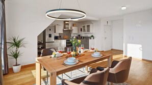 A modern dining area with a wooden table set for four, surrounded by leather chairs. A pendant light hangs above the table, and a potted plant is visible to the left. - Comfort kisses nature Skyline vacation apartment Goldbach (Goldbach)