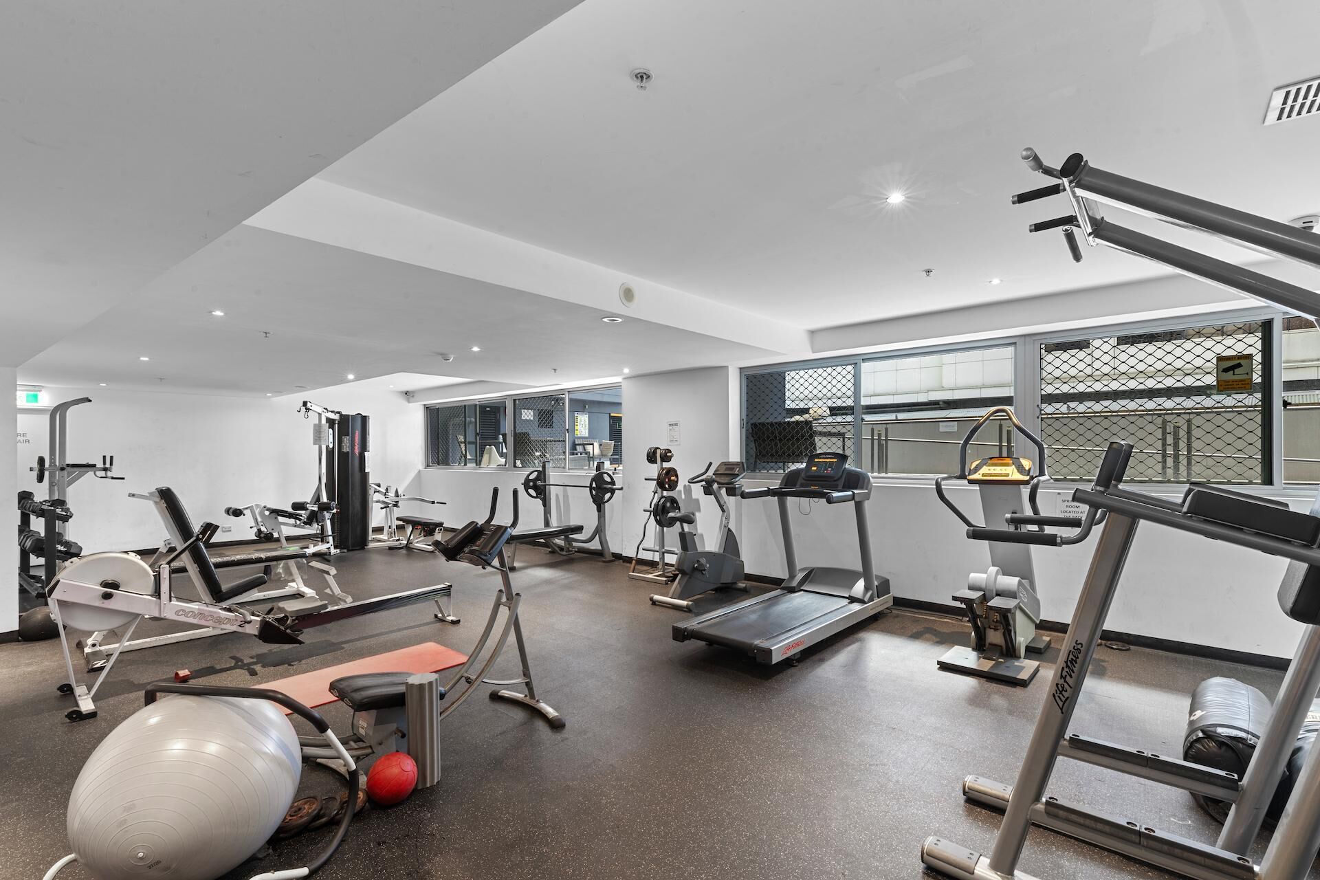 A gym with various exercise equipment, including treadmills, weight machines, and a stationary bike.