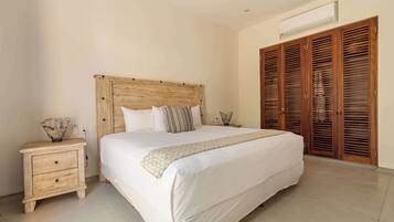Un dormitorio con cabecera de madera, una cama grande, una mesita de noche con lámpara y un armario de madera.