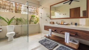A modern bathroom with a glass shower enclosure, a large mirror, and a wooden vanity.
