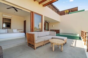 A modern outdoor living area with a sofa, a wooden coffee table, and a pool.
