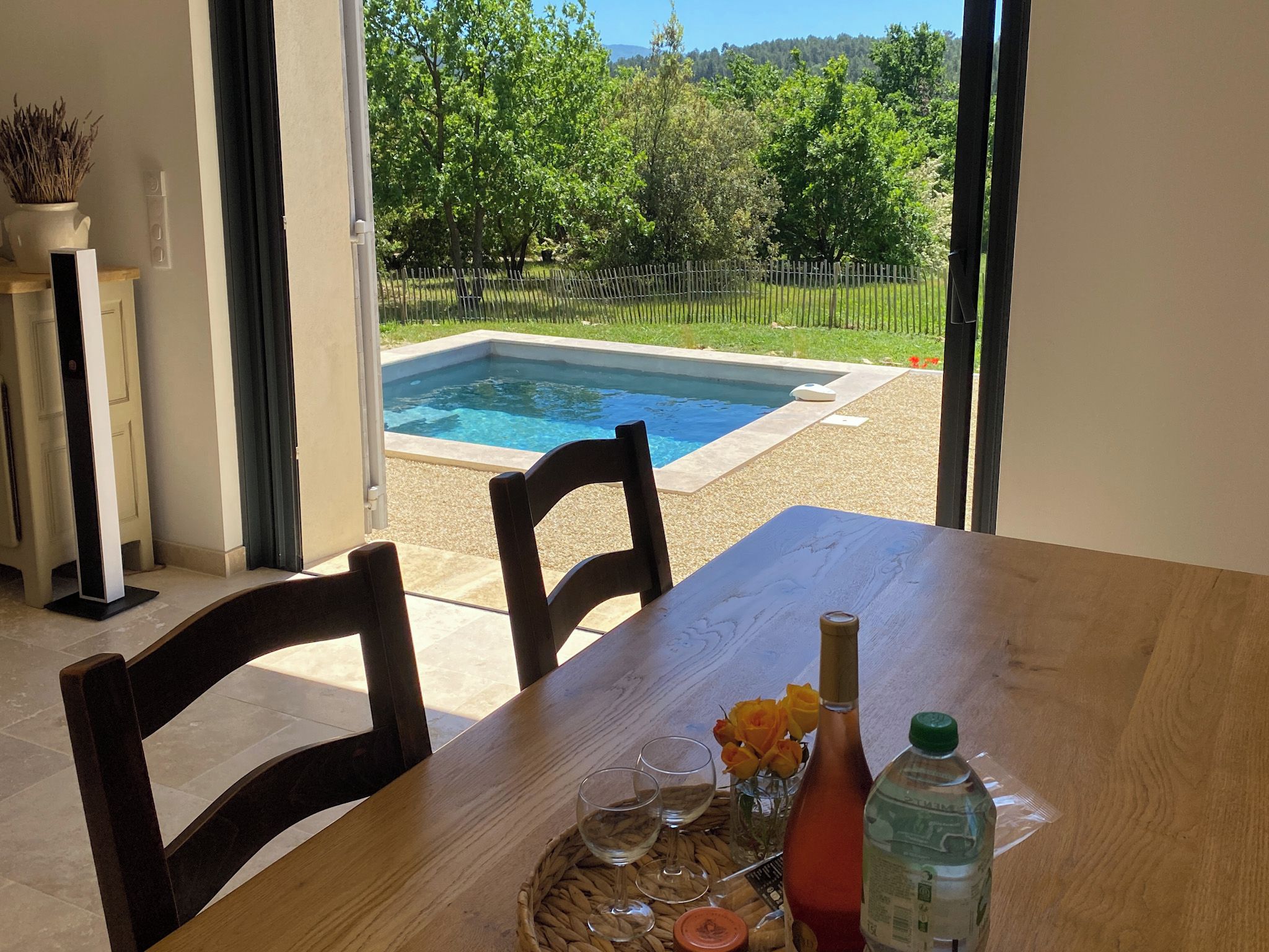 Un espace repas avec vue sur une piscine et un jardin clos.