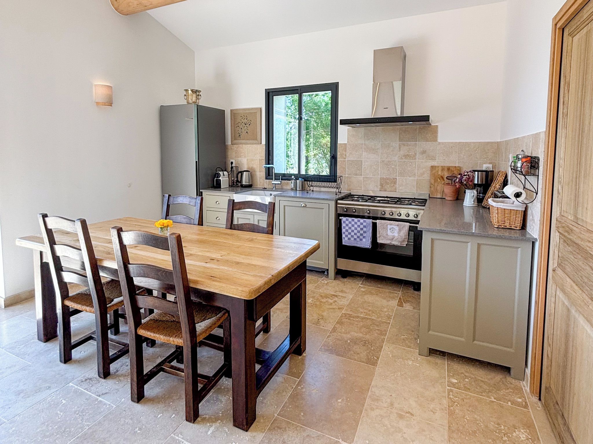 Une cuisine de taille réduite comprenant une table à manger, des chaises, une cuisinière et une fenêtre.