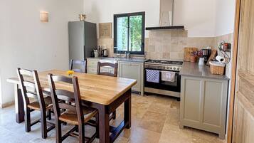Une cuisine de taille réduite comprenant une table à manger, des chaises, une cuisinière et une fenêtre.
