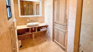 Une salle de bain avec un grand lavabo, un miroir et une porte en bois.