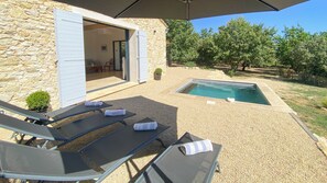 A stone building with a pool, outdoor seating, and a covered area.
