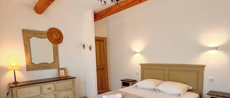 A bedroom with a bed, bedside tables, a dresser, a mirror, and a chandelier.