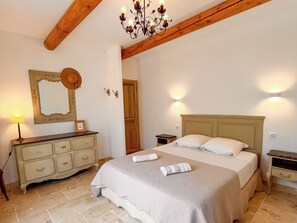 A bedroom with a bed, bedside tables, a dresser, a mirror, and a chandelier. - Charming 4‑star classified house – Provence, stunning view, private pool (Rustrel)