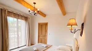 Ein Schlafzimmer mit einem Bett, einem Nachttisch, einer Lampe, einer Chandelier und einem Fenster mit Vorhängen.