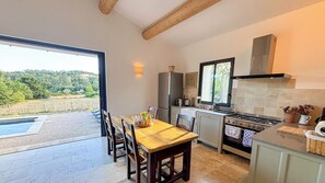 A modern kitchen with a large island, a dining area with a view, and a pool outside. - Charming 4‑star classified house – Provence, stunning view, private pool (Rustrel)