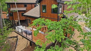 A wooden cabin with a deck, surrounded by trees. - The Willow at Treetop Villas (Lake Delton)