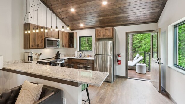 A modern kitchen with wooden cabinets, stainless steel appliances, and a large island. - The Willow at Treetop Villas (Lake Delton)