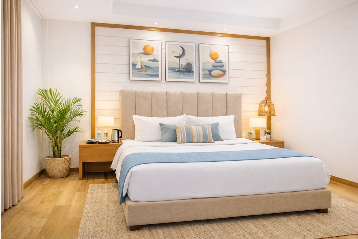 A modern hotel room with a large bed, a headboard with artwork, a bedside table with a lamp, and a potted plant.