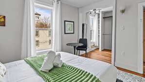 Ein Hotelzimmer mit Bett, kleinem Tisch, Stuhl und Blick ins Freie.