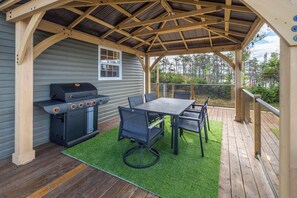 Un patio techado al aire libre con una parrilla, una mesa y sillas.