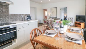 Une cuisine moderne dotée d’un four encastré, une table à manger mise avec des assiettes, des verres et une bouteille de vin.