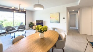 A modern dining area with a wooden table, grey upholstered chairs, and a vase of yellow flowers. - Modern and bright apartment near Estepona beach and center (Estepona)