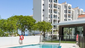 A swimming pool with a lifebuoy, a white building with balconies, and a clear sky. - Modern and bright apartment near Estepona beach and center (Estepona)