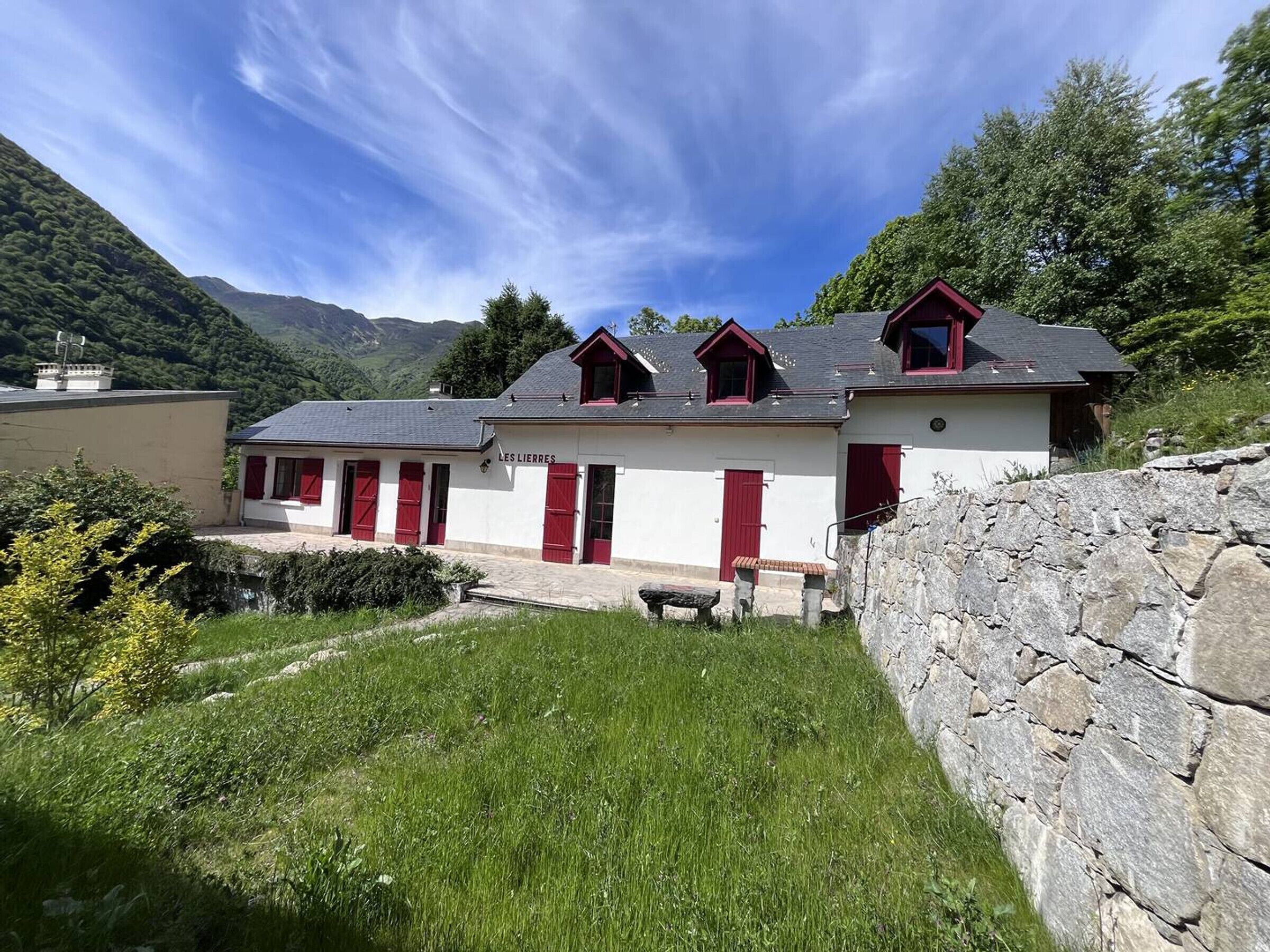 A row of white buildings with red doors and windows, set against a mountainous backdrop.