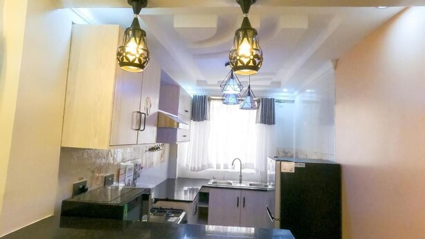 A kitchen with a black countertop, a sink, and two pendant lights. - Shirpelle Suites Kiamunyi (Nakuru)