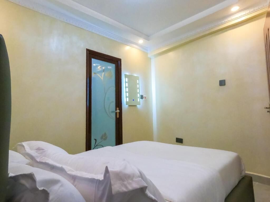 Una habitación de hotel con una cama, una puerta decorada con motivos florales e interruptor de luz en la pared.