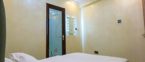 Una habitación de hotel con una cama, una puerta decorada con motivos florales e interruptor de luz en la pared.