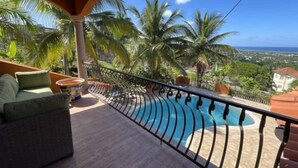 Un balcon avec une piscine, du mobilier d’extérieur et des palmiers.