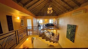 Un intérieur spacieux avec un plafond haut, un escalier doté de rampes décoratives et un lustre.