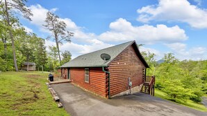 Une cabane en rondins avec un toit végétalisé, un petit porche et une antenne parabolique.