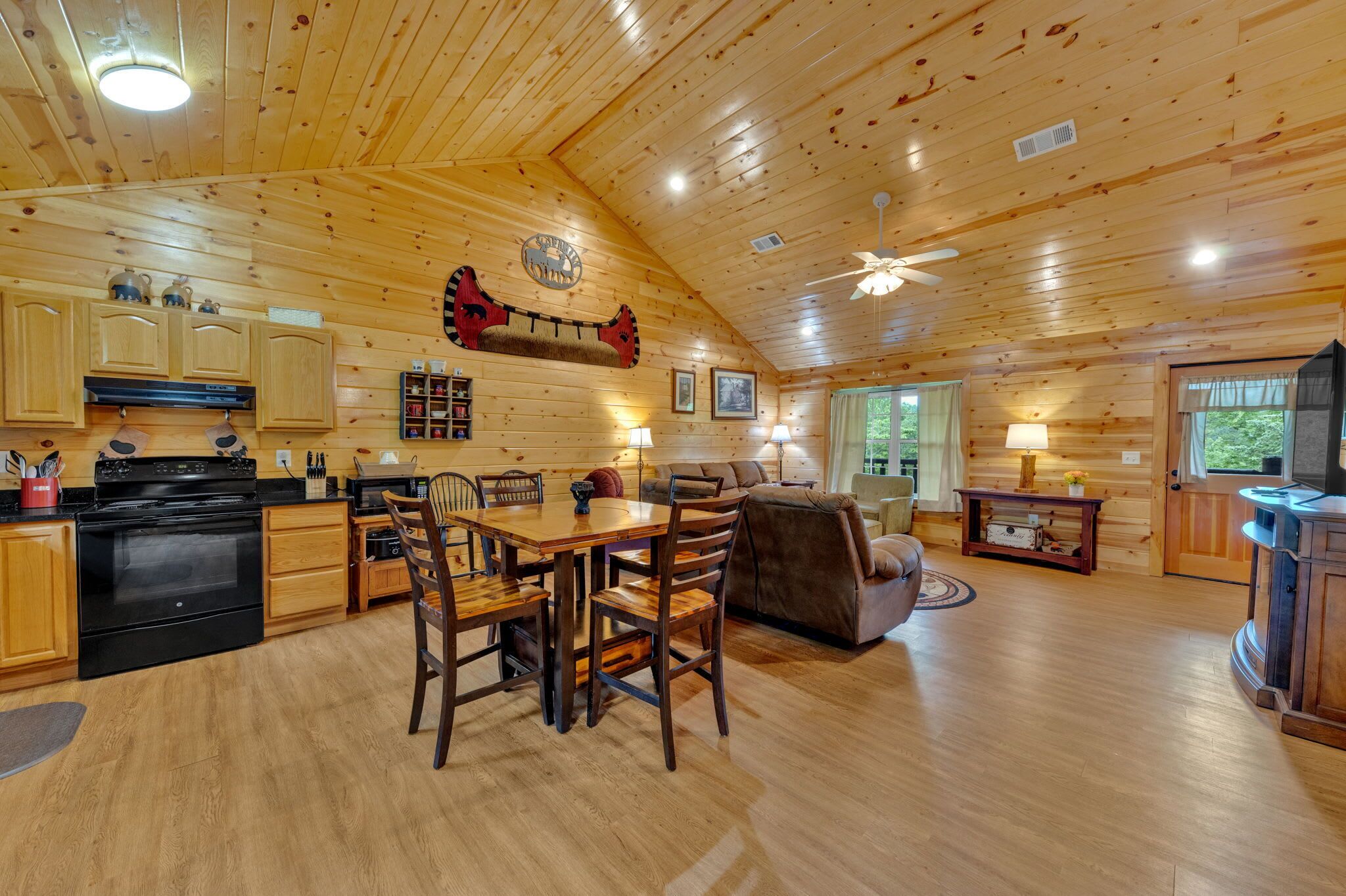 A wooden cabin interior with a kitchen, dining area, and living room.