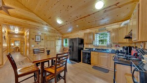L’intérieur d’une cabane en bois comprend un coin repas, une cuisine et une grande fenêtre.