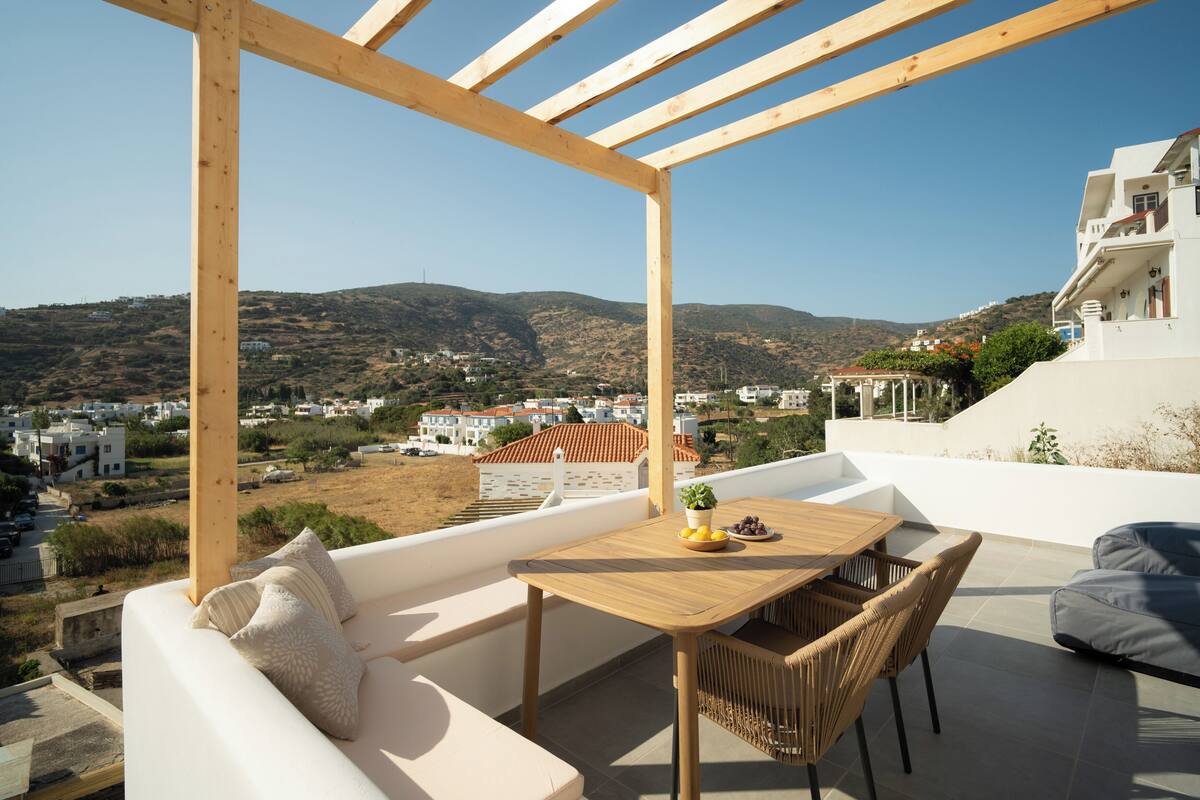 A balcony with a wooden table, wicker chairs, and a white sofa.