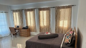 A bedroom with a bed, a desk, and a chair.