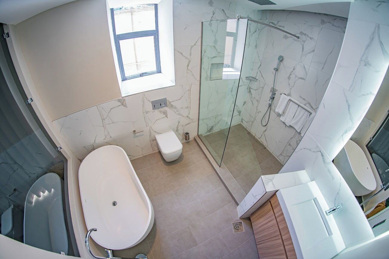 Ein modernes Badezimmer mit einer gläsernen Dusche, einer freistehenden Badewanne und einer Toilette.