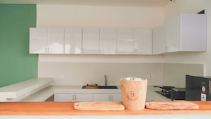 Una cocina moderna con armarios blancos, encimera de madera, un fregadero, una estufa y una cafetera.