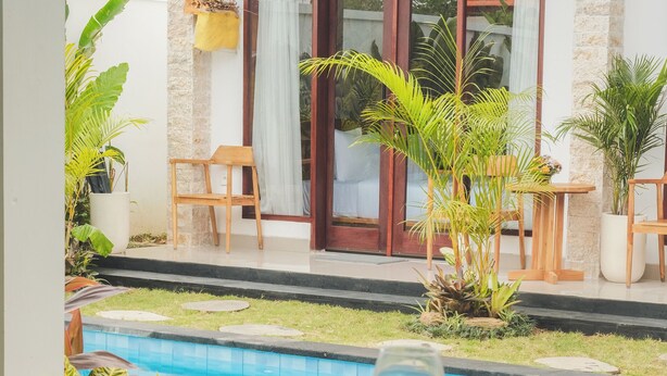 Zona de piscina con una mesa lista para comer, rodeada de plantas y una vista despejada de la piscina.