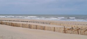 Een strand met een houten omheining die het zand van de oceaan scheidt.
