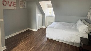 A bedroom with a sloped ceiling, a bed, a dresser, and a window. - Trowbridge House, Long Stay Disc, Parking, Wifi (Swindon)