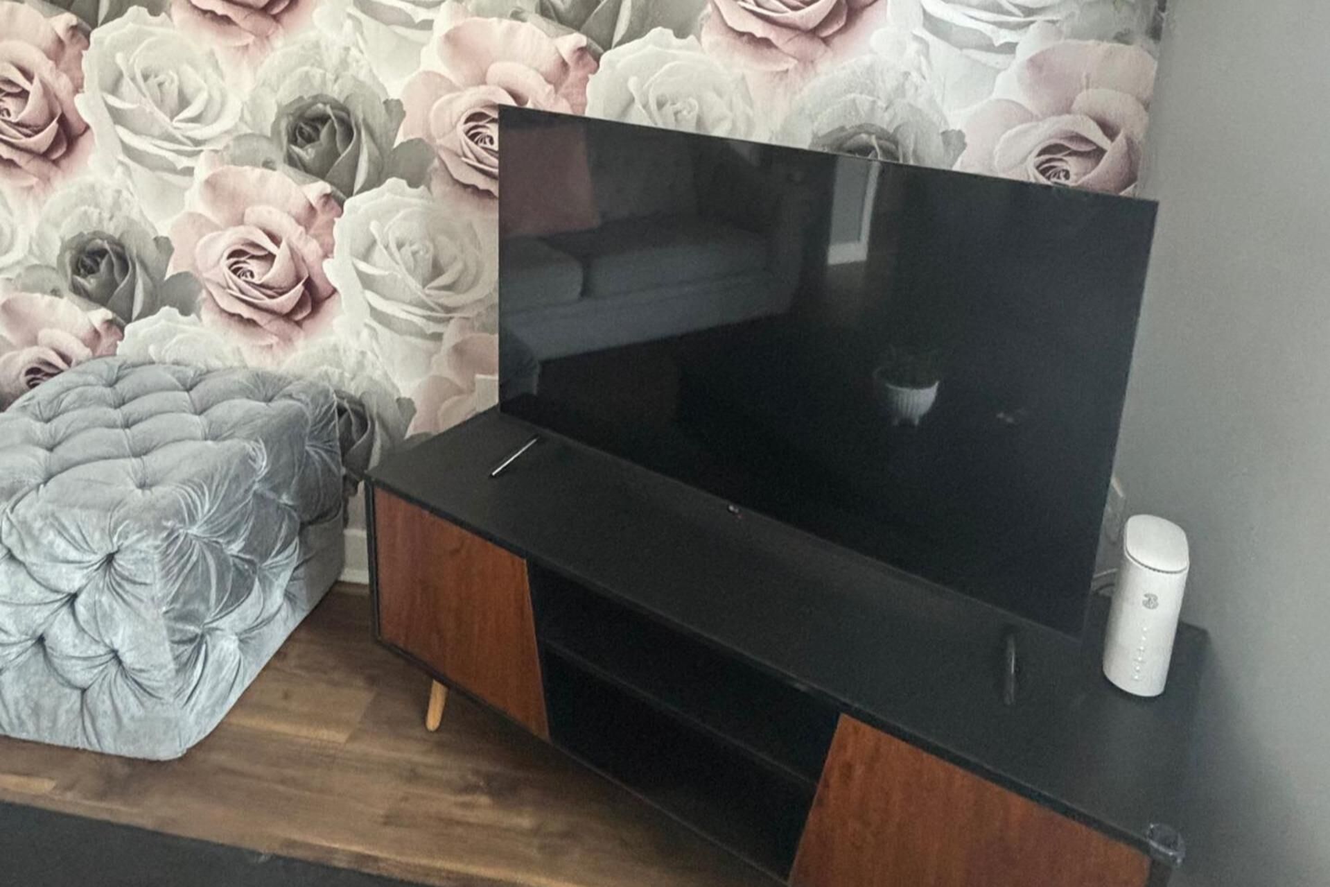 A flat-screen TV on a wooden TV stand with a white remote.