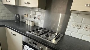 A modern kitchen with a gas stove, stainless steel cabinets, and a tiled backsplash. - Trowbridge House, Long Stay Disc, Parking, Wifi (Swindon)