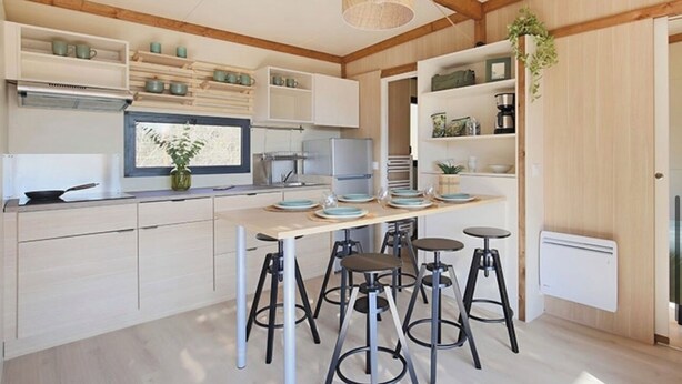 A modern kitchen with wooden beams, white cabinetry, and a central island with stools. - CHALET YOPLANI - UNDER THE CORSICAN SUN 6 PEOPLE (Sorbo-Ocagnano)